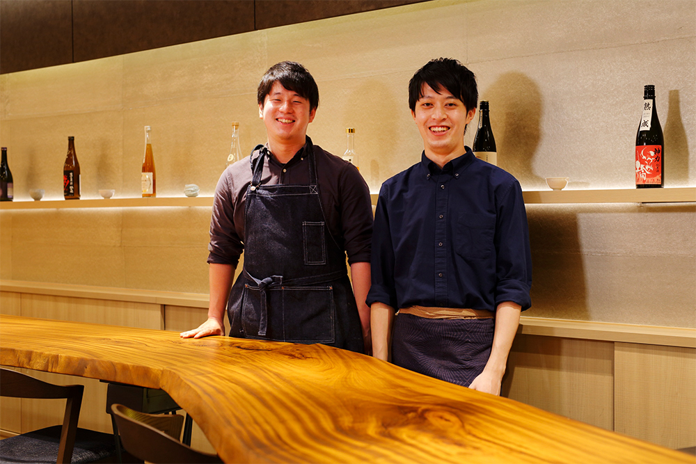 料理長の鈴木健也さん(左)は、ITベンチャーに3年勤めた後料理人を志し、2020年より島根県海士町の「島食の寺子屋」で1年間料理を学ぶ。2021年6月より「季苑」料理長に。唎酒師の土井貴文さん(右)は、大学在学中に日本酒に魅了され、2019年に唎酒師の資格を取得。翌年には山形県の桜川酒造で1カ月研修し、酒造りを学ぶ。2021年より現職。