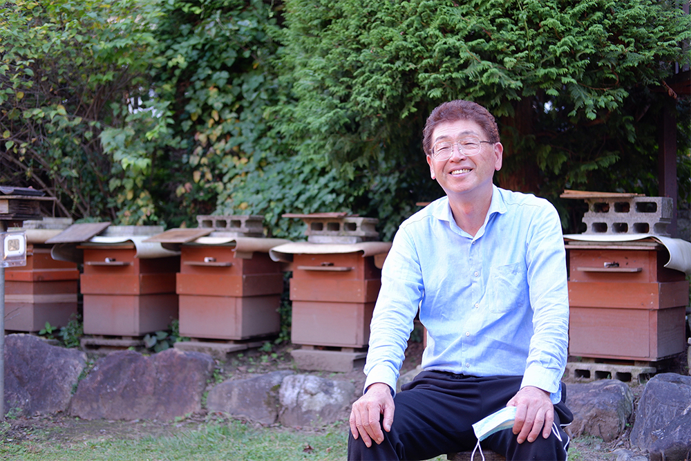 伊那市地蜂愛好会・山口政幸さん。「後継者育成が課題。ぜひ伊那市地蜂愛好会へのご加入をお待ちしています」。後ろに見えるのは採取したスガレを飼育している巣箱。