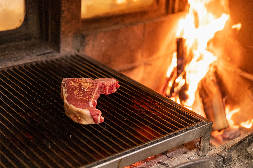 肉を冷蔵庫から出してカット(取材時は700g)、表面にオリーブオイルを塗って、網にのせる。塩はふらない。