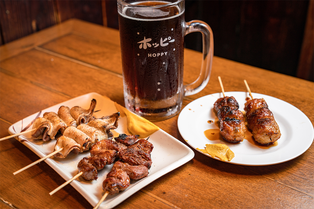 黒ホッピー(480円)と焼鳥。焼鳥は全21種類で、各2本から注文可。モツは芝浦から仕入れた新鮮なものを使用している。佐藤さんは、店で3杯、家で2杯飲むのが定番。