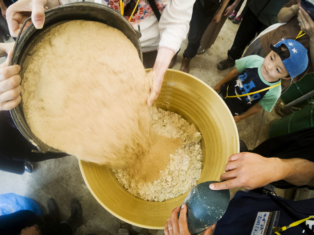 嫌気性発酵飼料作りを体験。おからと米ぬかを交互に混ぜてドラム缶に7層ほど重ねていきます。