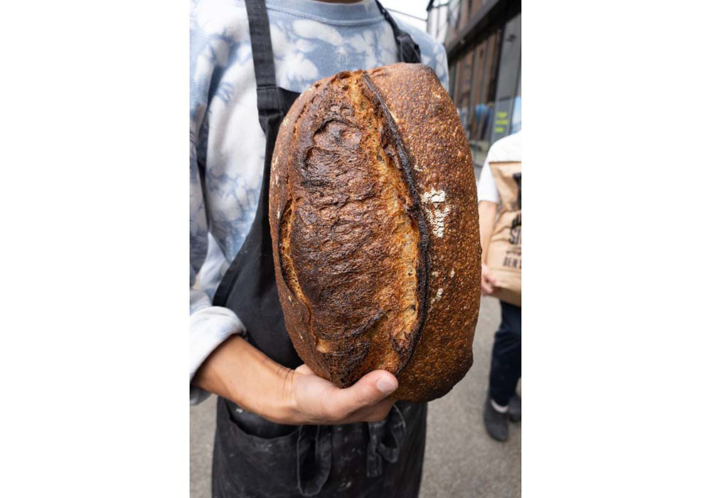 (写真)スウェーデン・オーランド島原産の在来種、オーランド小麦を20~30%配した「20% オーランド(Øland)」。イレブロで一番全粒粉の割合が少ないパンだ。「味がしっかりしたオーランド小麦を長時間発酵させて焼いているので、クラストは食べると繊細にはじけながら香ばしさと甘味を感じ、クラムからは乳酸菌発酵による長い余韻と小麦が持つ旨味が感じられます。1.3kgの重さがありますが、スライスすると食べやすく、サワードウが持つ奥行きを感じやすい。どんな食べ方にも料理にも合うので、初めて来た方にはまずはこのパンをお勧めしています」