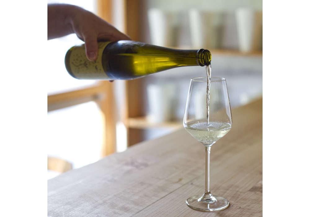(写真)アリントは微発泡酒で、ワインのような、とろける蜜のようにも見える色合い。注ぐ時にもふわりと麹の香りが漂う。