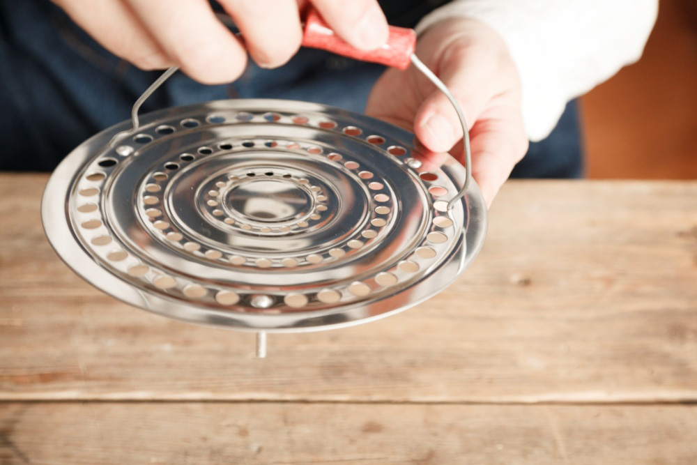 ［４］バケツから取り置いた取っ手を蒸し蓋の穴にかけて取り付ける。ダンパー（蓋）の出来上がり。